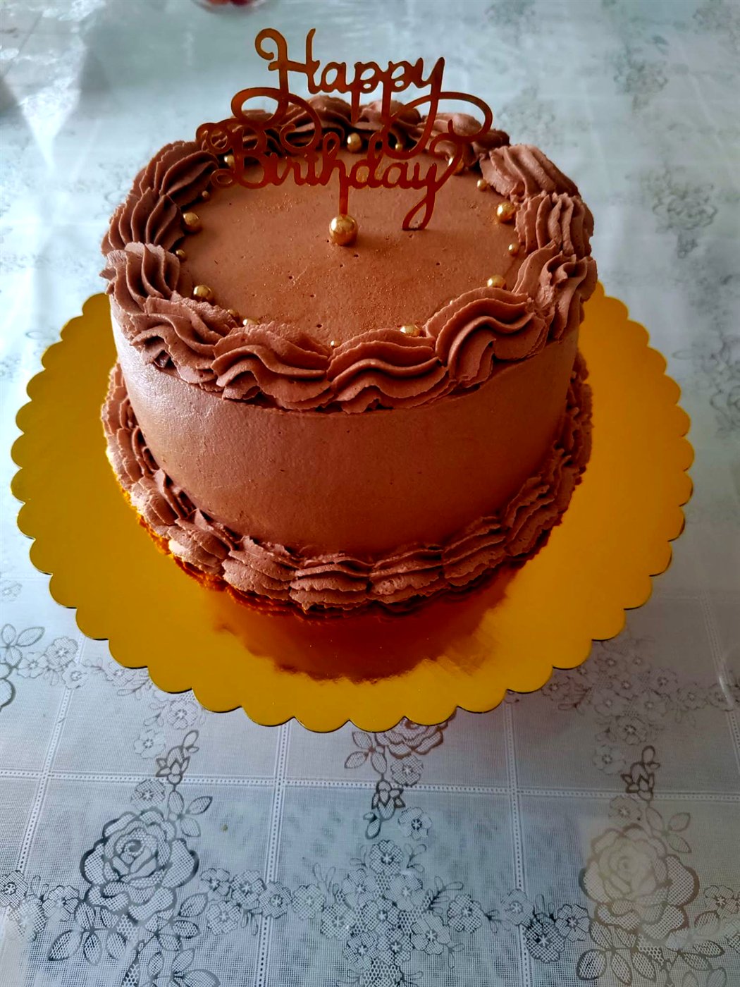 Tarta de chocolate con ondas de crema, perlas y cartel dorado Happy Birthday