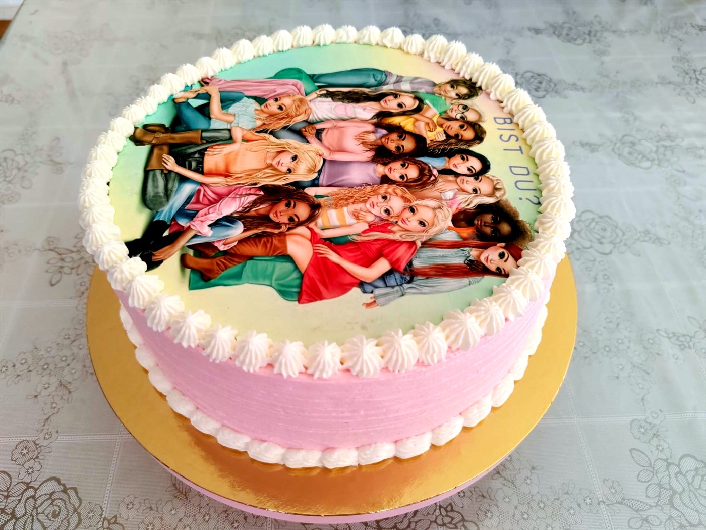 Tarta rosa con imagen comestible impresa y rosetones de crema blanca